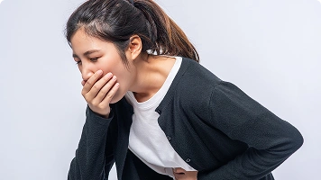 Man clutching abdomen near a toilet, suggesting digestive issues.