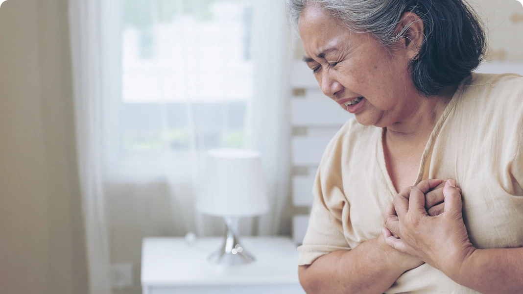 Older man clutching his chest in pain, with a red heart graphic and heartbeat line.